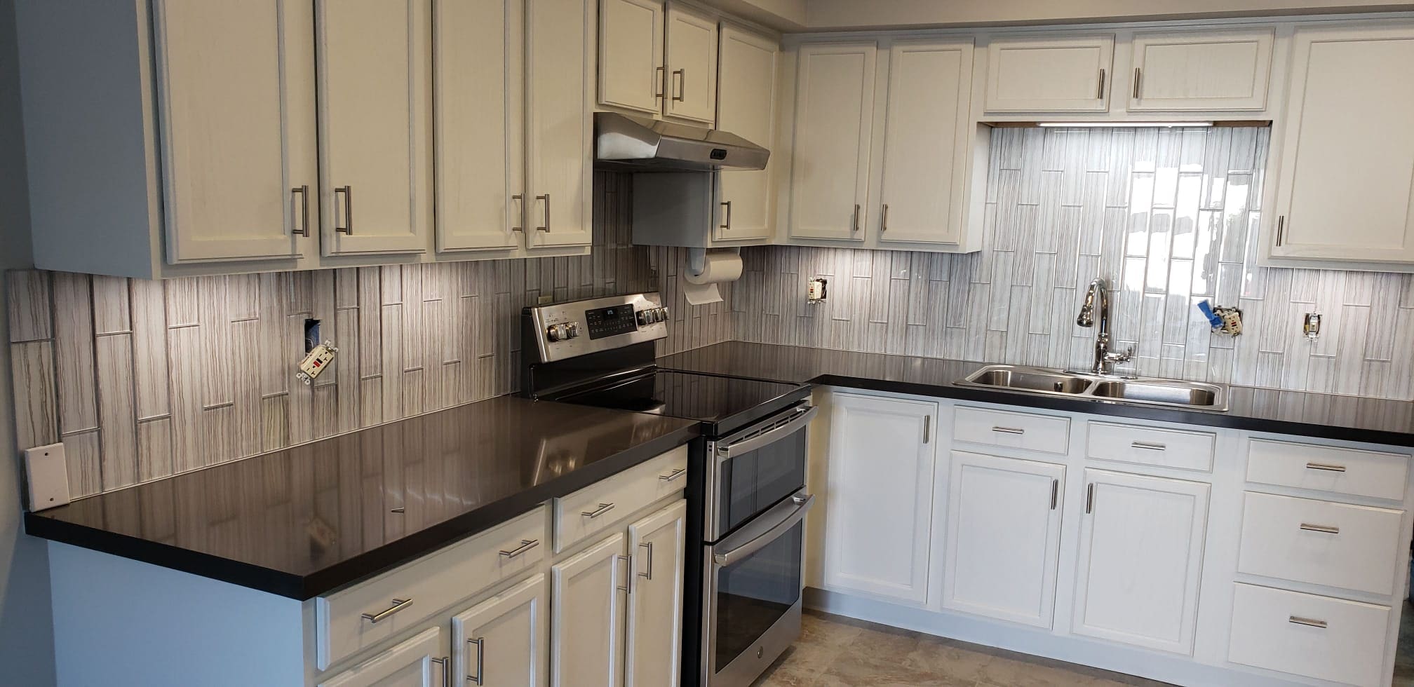 A kitchen with white cabinets and black appliances.