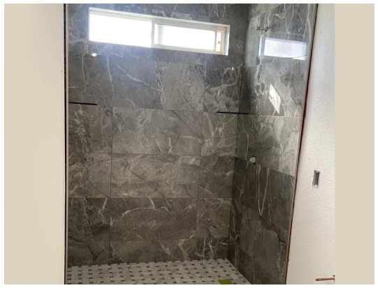 A bathroom with a large shower and tiled floor.