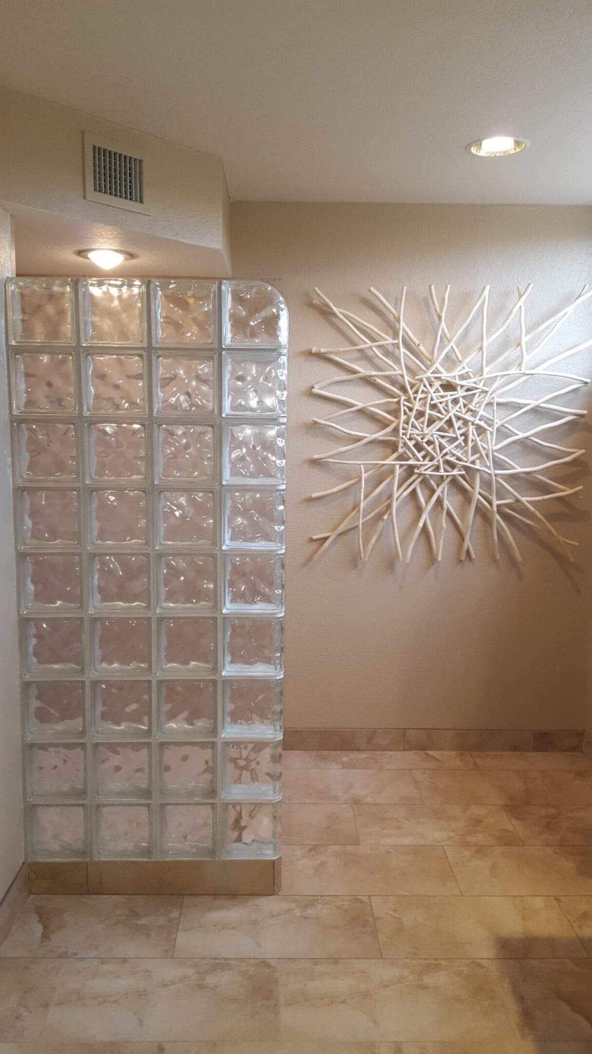 A glass block wall with a white design on the wall.