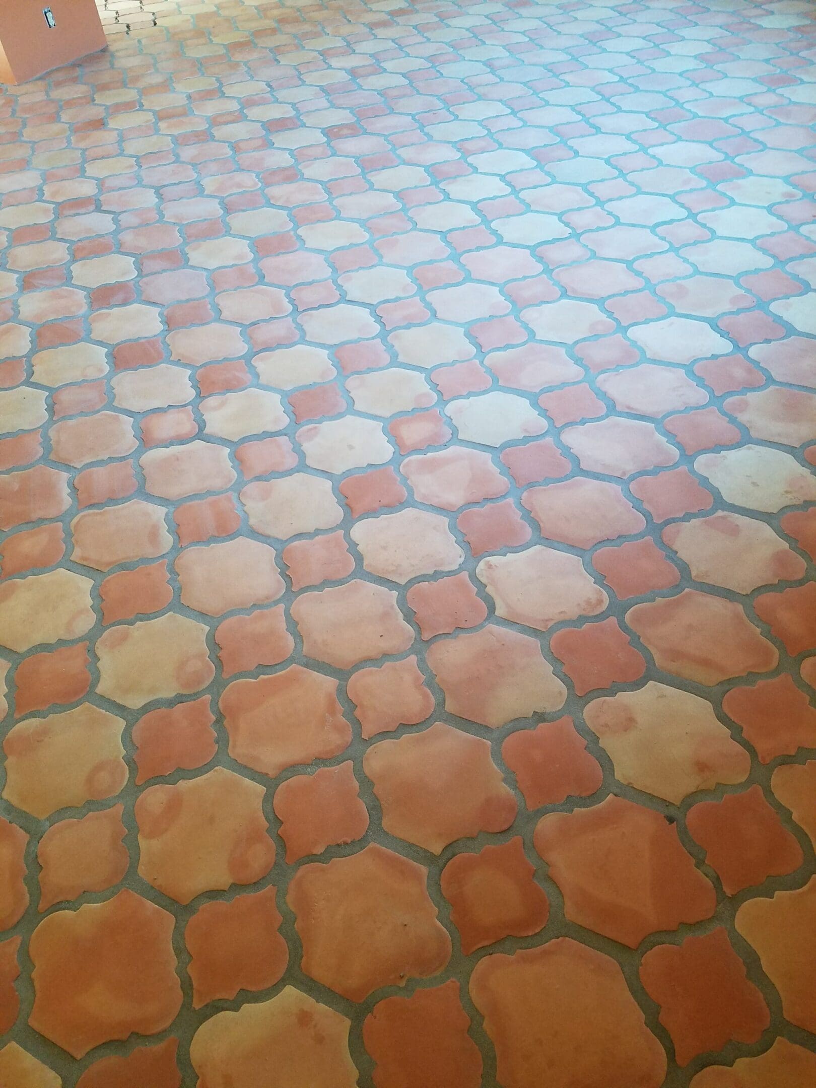A floor with a pattern of orange and brown tiles.