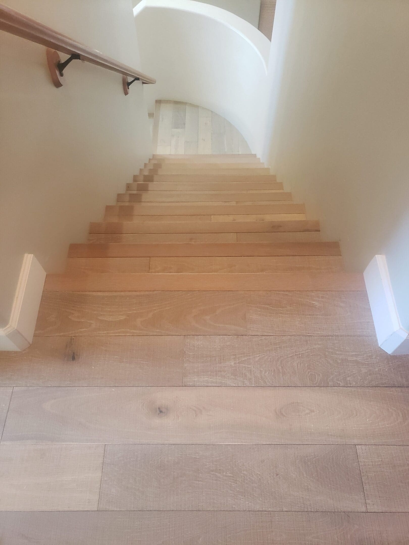 A long staircase with wooden steps and white walls.